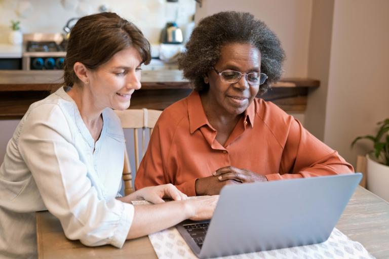 Woman teaching an older person using a laptop