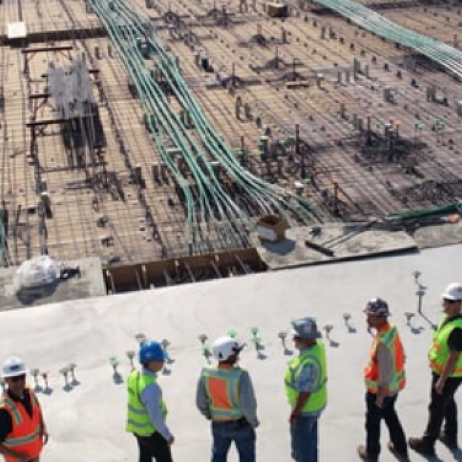Construction workers standing on roof overlooking building construction site